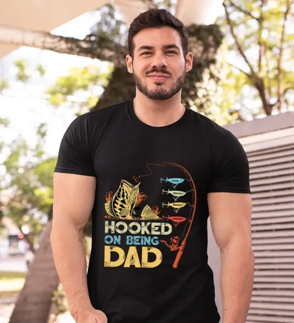 Personalized-Hooked-On-Being-Dad-Fishing-Shirts-1.webp Personalized Hooked On Being Dad Fishing Shirts, Vintage Dad Shirt, Best Dad T-Shirt, Funny Fishing Shirts For Men, Gifts For Fisherman